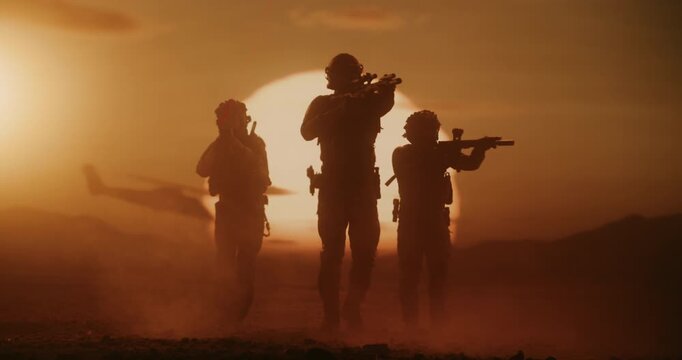 Three Male Soldiers in Advanced Combat Gear March Across a Desert Warzone, Silhouette by a Massive Air Force Formation of Helicopters. Patrol With Rifles, Helmets,  Modern Military Battlefield