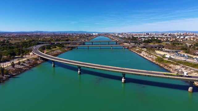 Aerial view of several road bridges crossing the Turia river channel in Valencia, Spain, with urban skyline, traffic infrastructure and Mediterranean coastal city landscape in the background