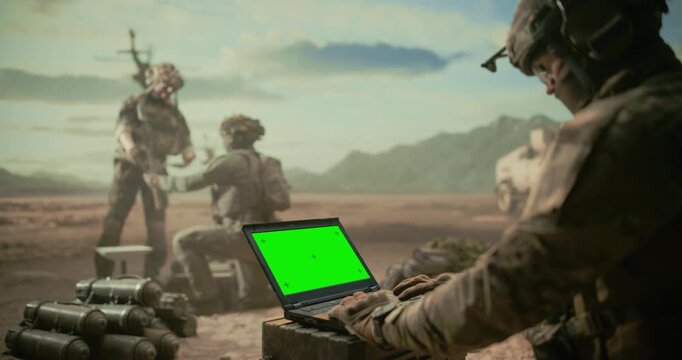 Soldiers Operating Green Screen Chroma Key Laptop for Enemy Tracking, Surveillance, Tactical Coordination as a Helicopter Approaches Targets Middle East Desert Combat Zone. Battlefield Command Post