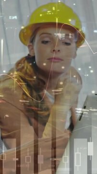 Vertical video: Woman on site, peer pointing, tapping tablet reading overlaid charts, deciding plan