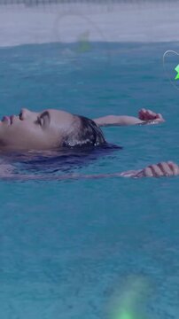 Vertical video: Teen floating in teal pool, green glow sparking tech icons drifting past her right
