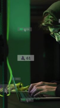 Vertical video: Coder typing on laptop by rack, badges pulsing and counts rising, looking up