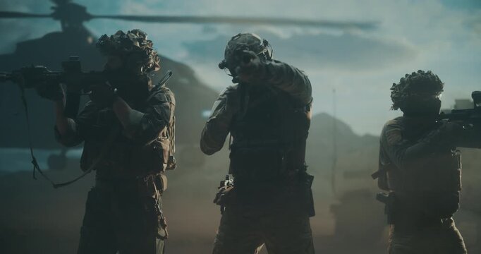 Three Male Special Forces Soldiers Advance From a Helicopter Landing in Desert War Zone, Weapons Ready, Executing a High Tech Combat Operation for Strike Warfare Support. Cinematic Action of Military