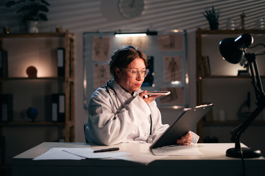 female doctor records audio recommendation using phone at hospital. Giving recommendation and medical advice. Medicine
