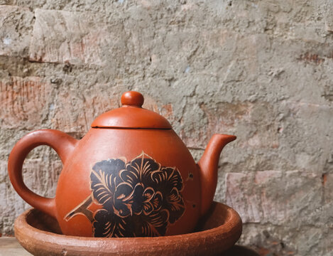 Traditional Clay Teapot with Rustic Brick Wall Background