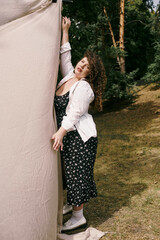 Fototapeta premium Curly haired woman embodies confidence in a floral dress amidst nature's beauty