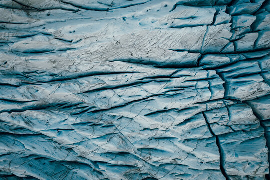 Aerial view of the Svinafellsjokull glacier's icy expanse, a tapestry of deep blue crevasses and stark white ridges, Iceland.