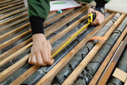 Measuring geological core samples with tape measure in industrial setting