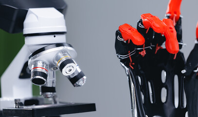 Microscope adjacent to robotic prosthetic gripper tools on lab bench © Parilov