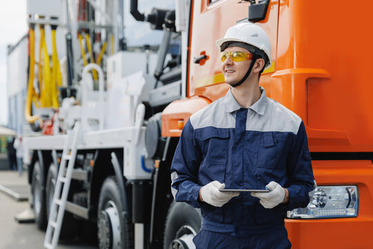 Driver man in uniform with tablet computer controls geology drilling truck for oil. Concept banner automated hard work with online internet