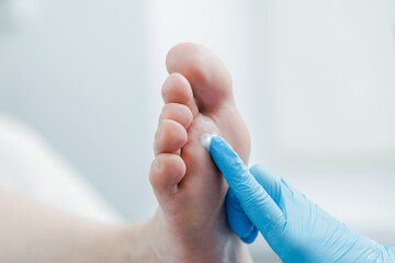 Naklejka premium Close-up of gloved hand applying cream to foot