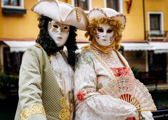 Obraz premium Venice, Italy - February 10, 2026: Elegant masked figures in ornate costumes at Venice Carnival, showcasing intricate details and vibrant colors against a historic backdrop