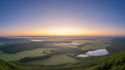 Fototapeta premium Panoramic Sunrise Over Misty Green Valley with Lakes and Rolling Hills, Scenic Aerial Landscape of Peaceful Countryside Nature at Dawn
