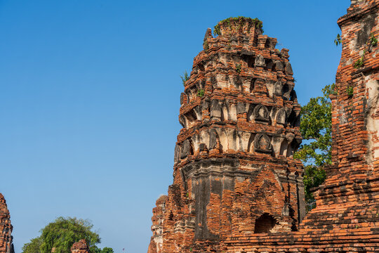 Row of ancient red brick Buddhist prangs and ruins against a clear blue sky in Ayutthaya