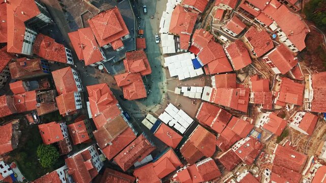 Top down rotating drone view over red rooftops of Cudillero town in Asturias, Spain with birds flying above narrow streets.