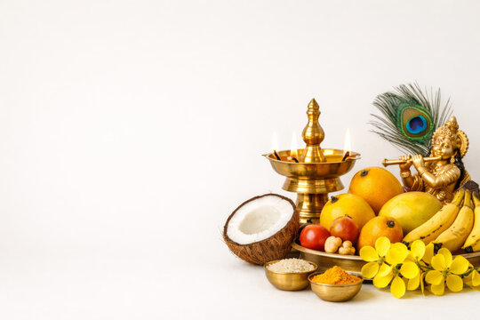 Vishu Kani setting with Lord Krishna idol, Nilavilakku lamp, fruits and flowers on white background.