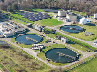 Aerial drone view of wastewater treatment plant with clarifier tanks and solar panels for sustainable infrastructure 