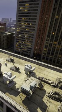 A rooftop space shows scattered construction materials. Nearby buildings are lit up, and the city skyline stands out under a dark sky. The scene reveals urban development in progress.