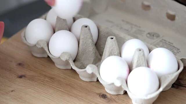 Woman's hands taking fresh chiken eggs out of the cardboard box