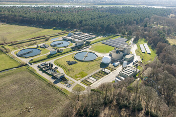 Drone aerial view of municipal wastewater treatment facility with clarifier basins in rural landscape 