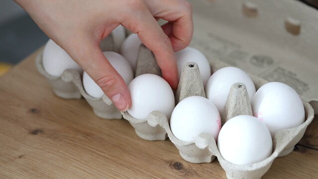 Woman's hand taking fresh chiken eggs out of the cardboard box