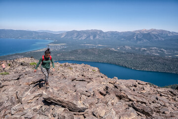 A woman is hiking up a mountain and looking out over a lake