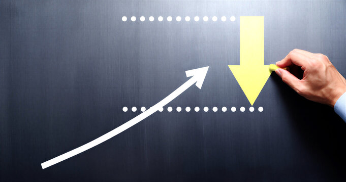 Hand adjusting upward and downward trend arrows on a chalkboard