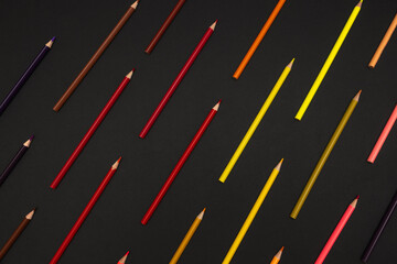 Geometrically Arranged Colored Pencils Top View on Black Background