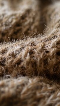 Vertical video: Lens adjustment shifting focus across brown knit on table, revealing yarn fibers