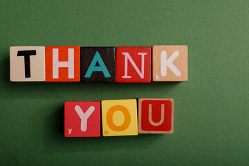 Colorful wooden blocks spelling Thank You on a green background. Perfect for expressing gratitude and appreciation.