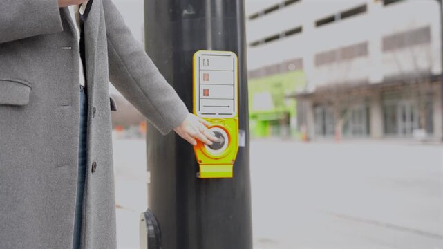 Close up of pedestrian crossing button on city street with person waiting near crosswalk