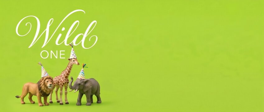 Wild One birthday party with lion, giraffe, and elephant wearing party hats, celebrating a first birthday with a jungle theme and copy space Concept of childhood, celebration, and animals