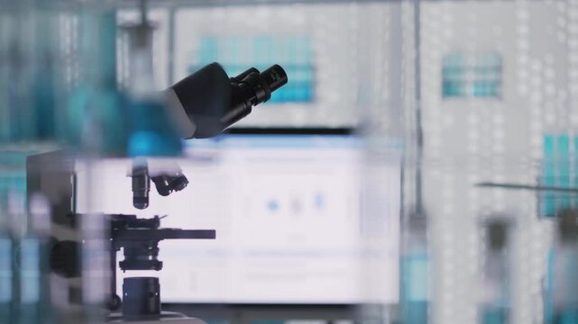 Biochemistry research laboratory for research of human disease. Computer screen displaying test results with a microscope standing nearby. Selective focus