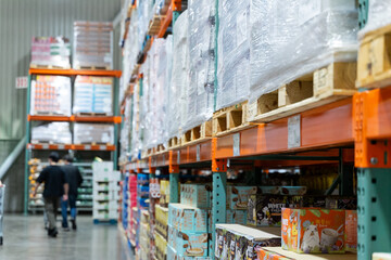  A wide interior photograph of a large warehouse-style wholesale shopping center featuring long...