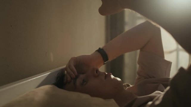 Close up shot of listless Caucasian zoomer scrolling on smartphone in bed, feeling bored and suffering from insomnia at dawn