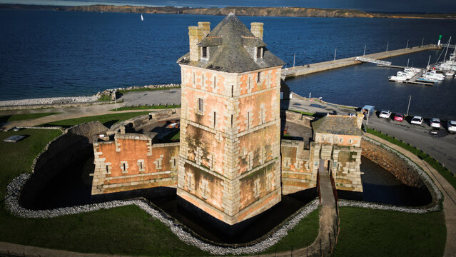 Aerial view of a fortress standing stalwart against the azure sea, its stone walls aged by time, reflecting the sun's golden kiss, Camaret-sur-Mer, Bretagne, France.