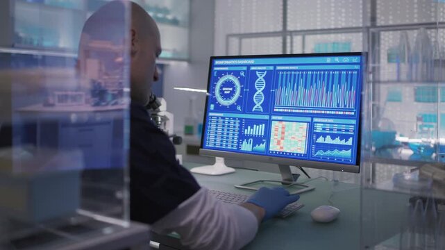Male scientist or a doctor in protective glove working in a medical research laboratory. Typing on a computer and examining the data