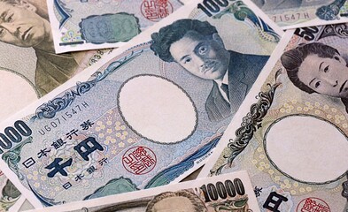 Japanese yen money bills pile on table. Japan banknotes of JPY currency close up. © Larysa