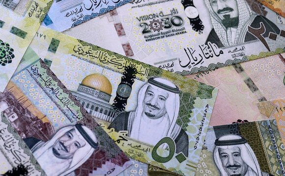 Saudi riyal money bills pile on table. Saudi Arabia banknotes of SAR currency close up.