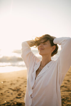 Beautiful 40 years old woman relaxing on the beach at sunset.