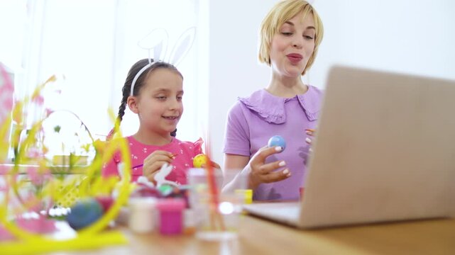 A mother and daughter enjoy an Easter egg decorating session together, connecting virtually with others