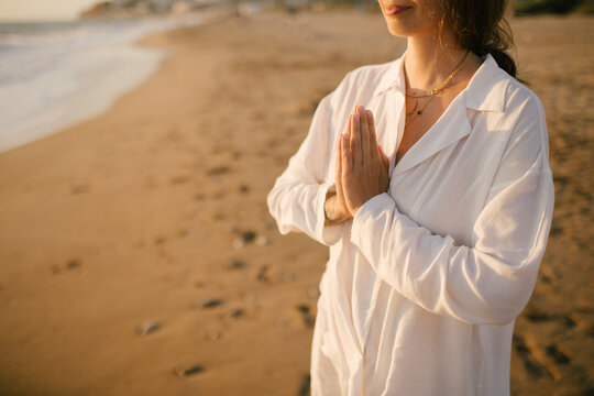 Beautiful 40 years old woman having yoga exercises on th beach at sunset.