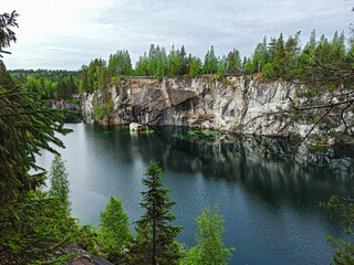 Fototapeta premium Quarry lake reflecting forest and cliffs.
