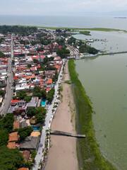 Fototapeta premium A vertical drone shot captures the lively town of Chapala, Mexico, along the shores of Lake Chapala. The image features a promenade, a sandy beach, traditional architecture, and green algae on the lak