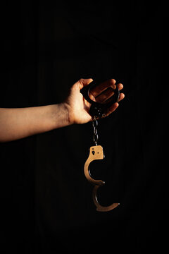 Handschellen von einer Frau gehalten im Halbdunkel