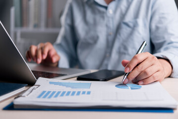 Fototapeta premium businessman hands working on laptop and analyzing financial data charts, graphs, and reports at office desk. Business planning, strategy, marketing, accounting and auditing concept.