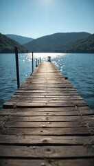 Fototapeta premium Wooden pier extends over calm blue water towards distant green hills under bright sunlight. Natural landscape offers peaceful serene atmosphere for relaxation, outdoor activities. Sunny day on lake.