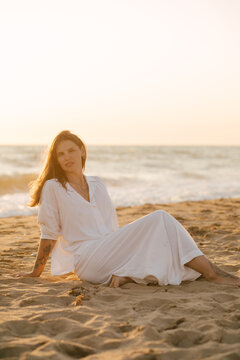 Beautiful 40 years old woman relaxing on the beach at sunset.