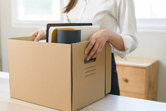 Unemployed, quite job. Desperate asian young businesswoman resigning from company, hand holding cardboard, packing belongings, stuff into box, layoff or changing work. Resignation, employment concept.