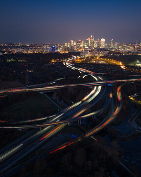 Aerial view of glowing trails of light weaving through the Westkreuz interchange against the backdrop of the Frankfurt skyline, Frankfurt, Hessen, Germany.